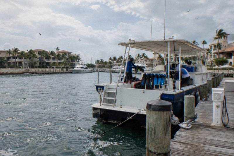 Small dive and snorkel boat tied at a marina dock with fins, masks, and a crew member aboard