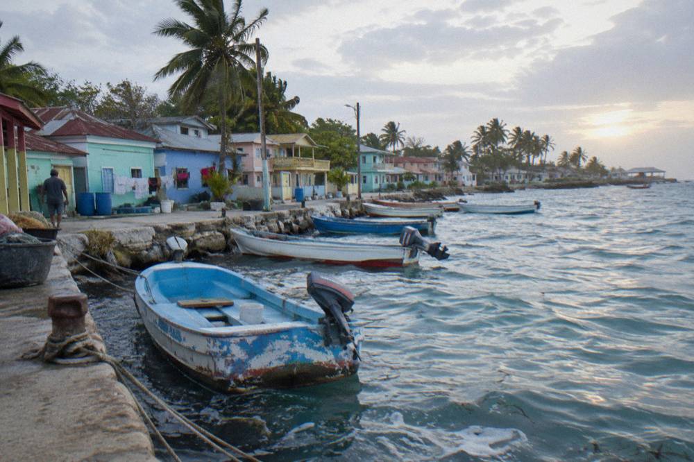 Small fishing boats moored along a quiet Caribbean coastal village at dawn