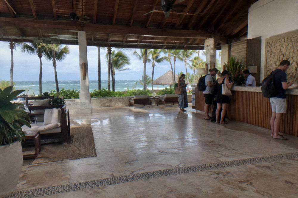 Open-air resort lobby with several travelers with backpacks at the reception counter
