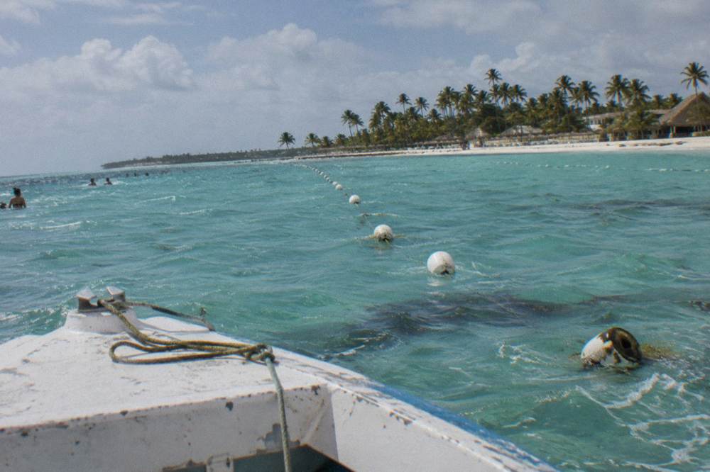 Buoy markers lining a shallow turquoise navigation channel toward a sandbar