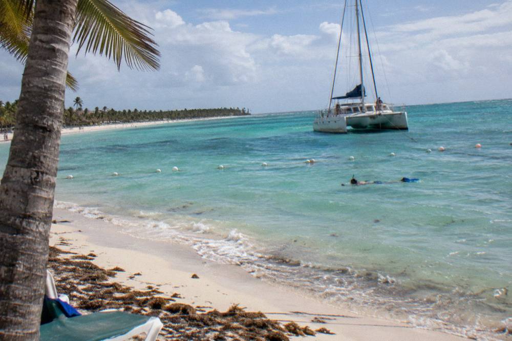 A catamaran anchored near a shallow sandbar with clear turquoise water