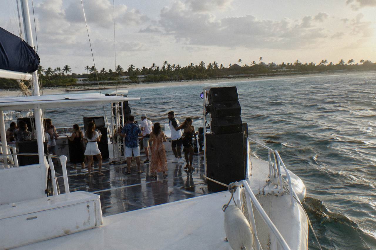 Catamaran deck with speakers and dance floor under an open sky on calm Caribbean water