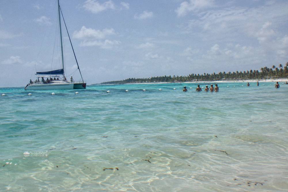 Shallow turquoise sandbar with a moored catamaran and clear water