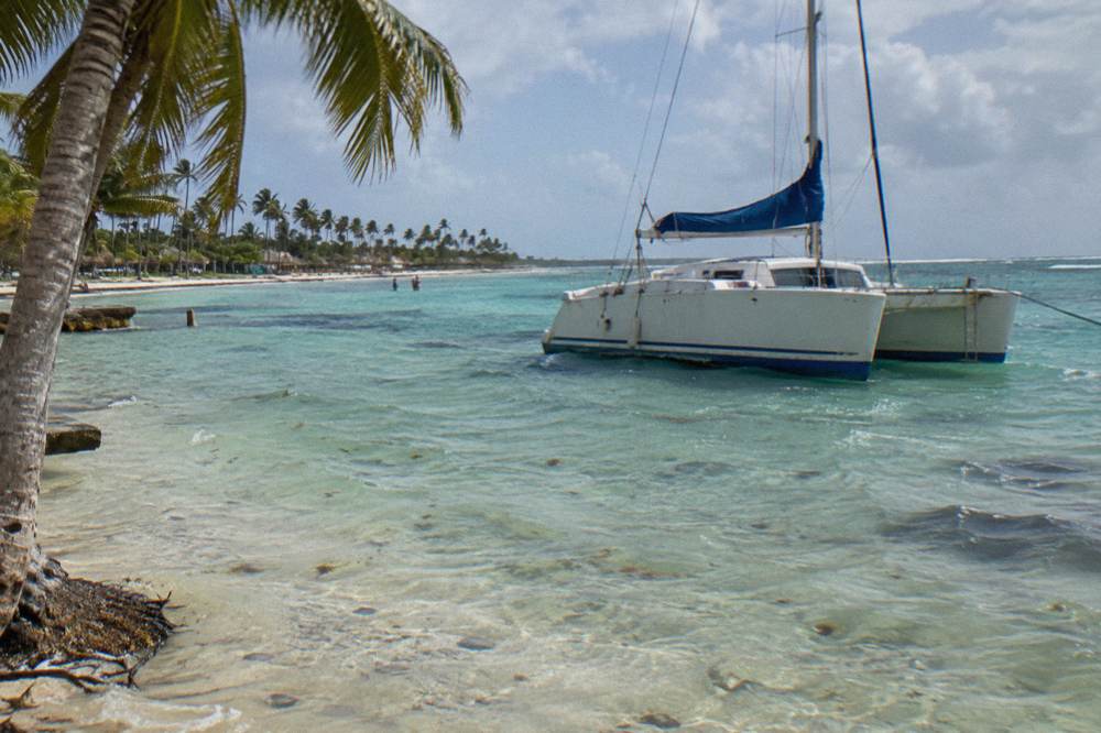 A catamaran anchored in clear shallow water at a natural pool sandbar