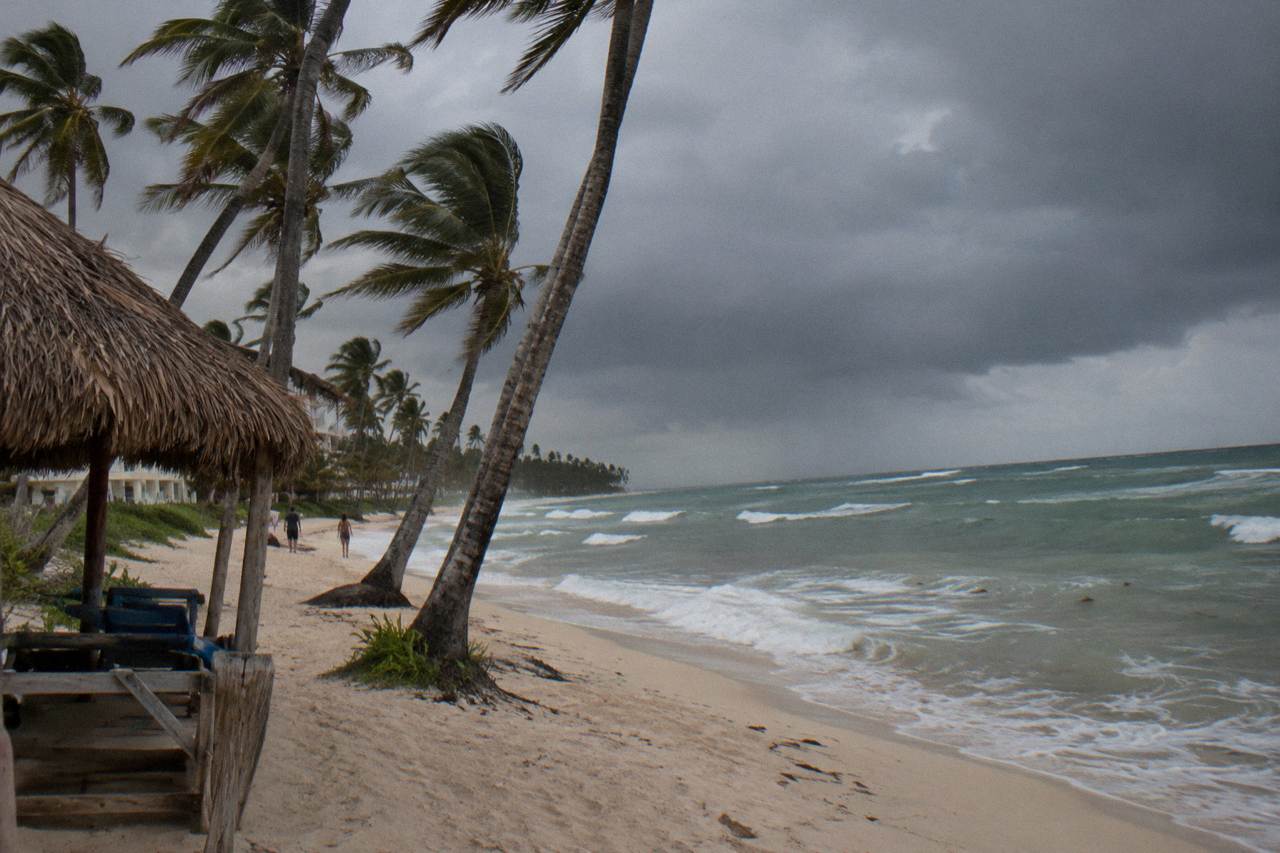 Rain clouds gathering over palm trees along an empty Caribbean beach