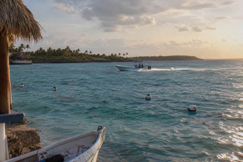 A speedboat crossing open turquoise Caribbean water toward a distant treeline island