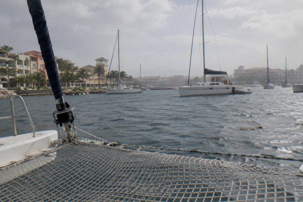 Catamaran net deck with calm bay and moored sailboats in the background