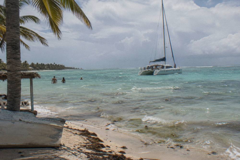 A catamaran anchored in shallow turquoise water near a sandbar off the Dominican Republic coast