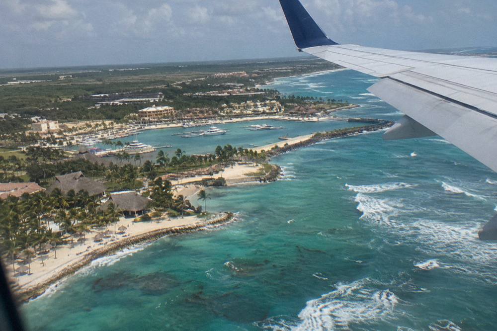 Airplane wing above turquoise Caribbean coastline on approach to Punta Cana