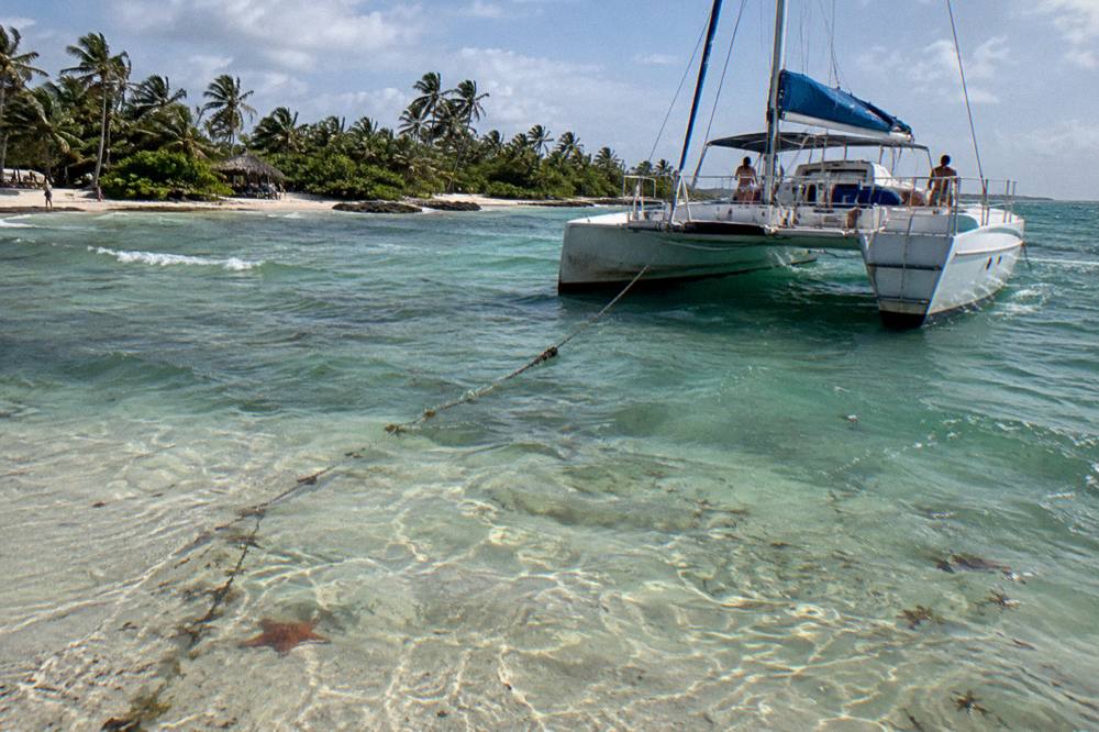 Catamaran at anchor near a shallow sandbar with clear water