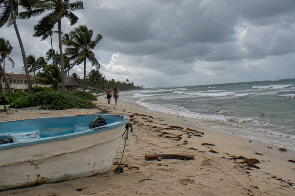 Empty palm-lined beach in Punta Cana under heavy gray storm clouds before rain