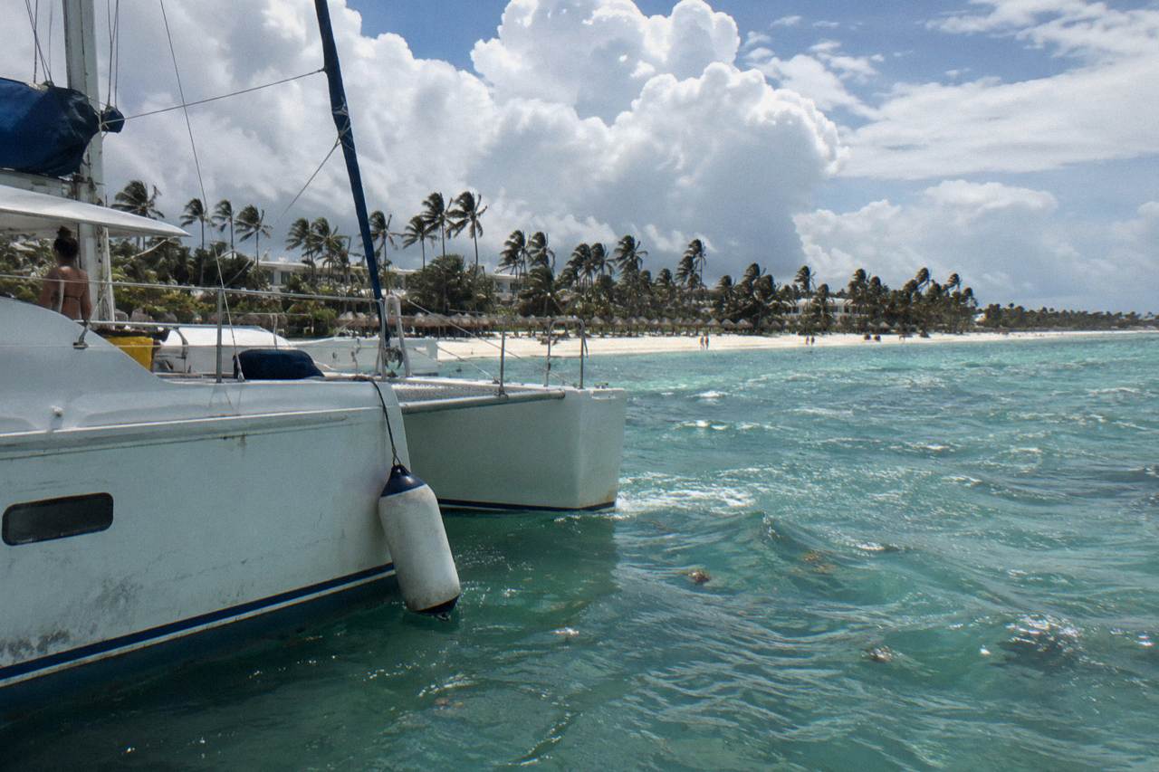 Catamaran anchored on calm turquoise water near the Bavaro coastline under a partly cloudy sky