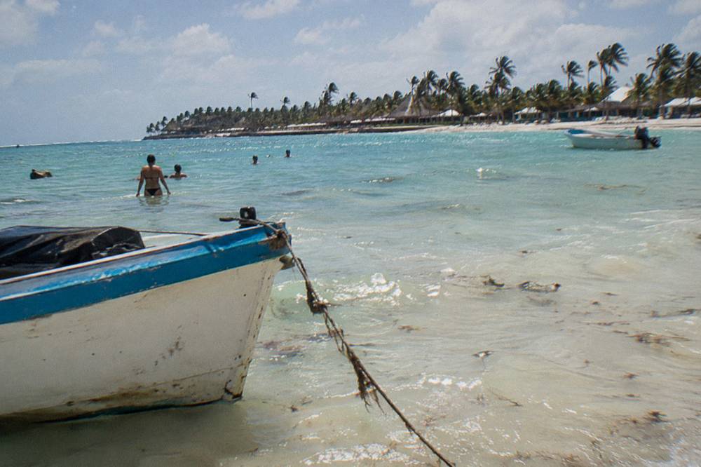 A floating tray of drinks beside a boat ladder in shallow turquoise water