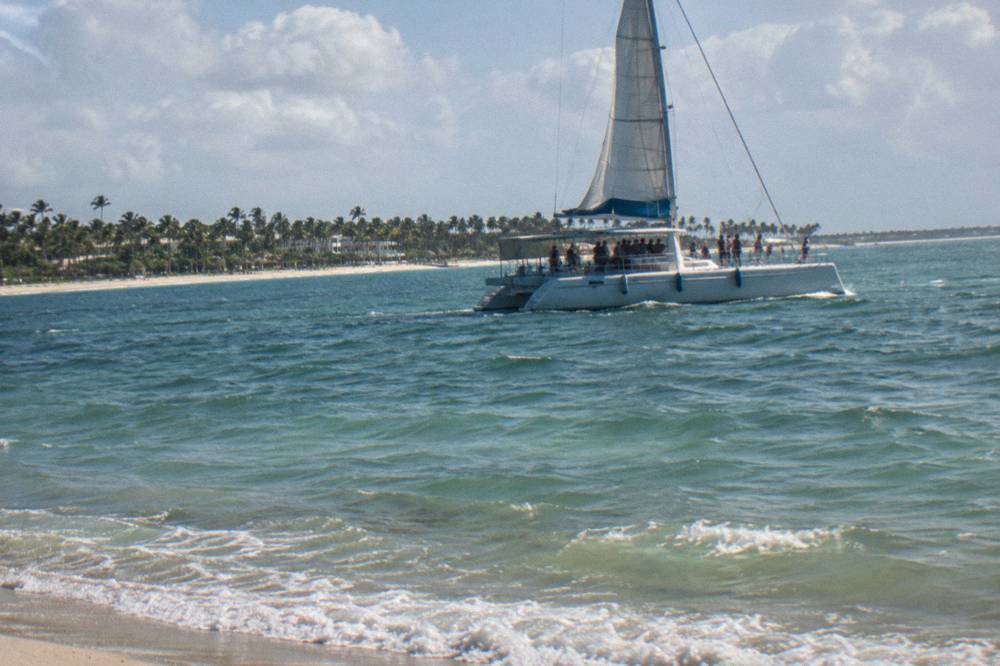 Guests dancing beside a bar counter as a catamaran sails along the Bavaro coast