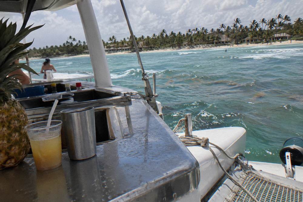 Bottles of rum and local beer lined up on a boat bar counter in the sun