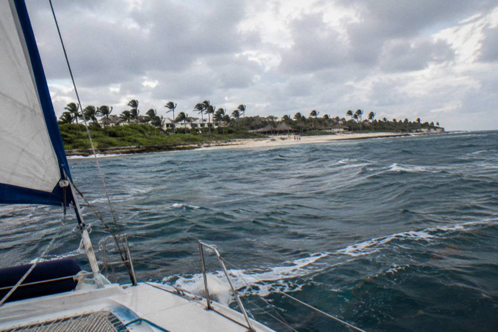 Catamaran cruising back toward the Punta Cana coast under an afternoon sky