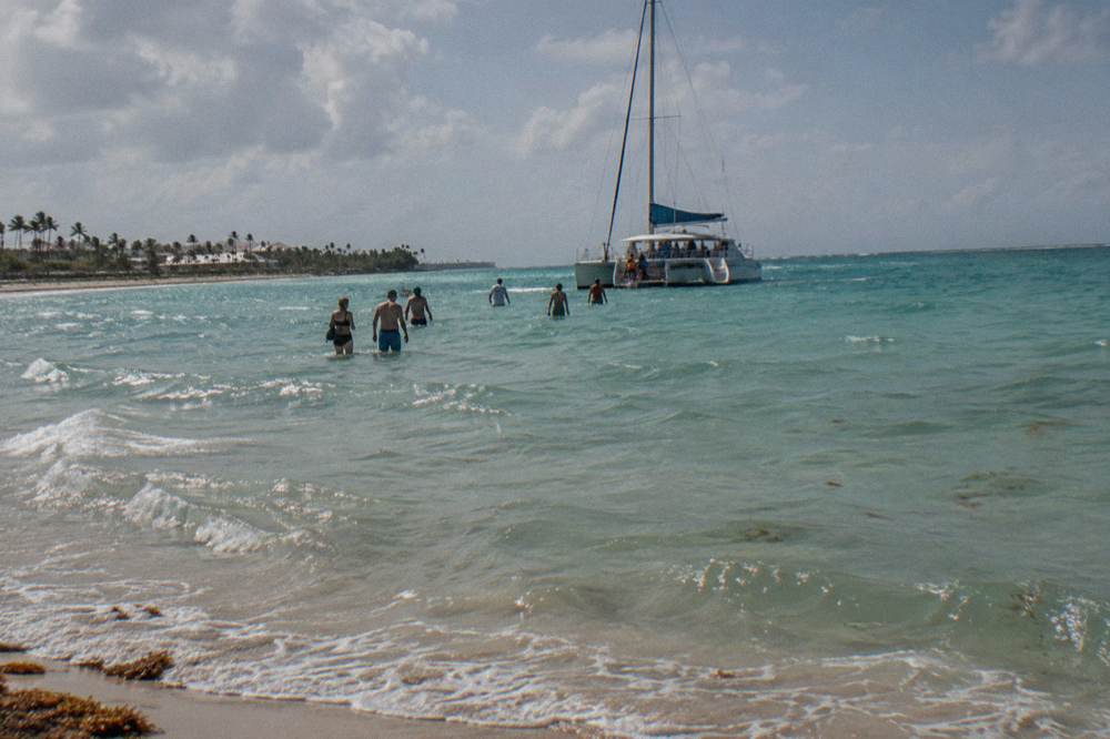 Group boarding a catamaran from a tropical beach in the late afternoon