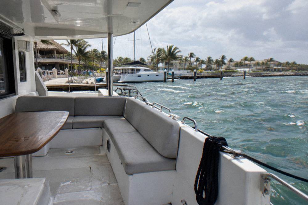 A wide deck of a catamaran with seating and a shaded lounge area