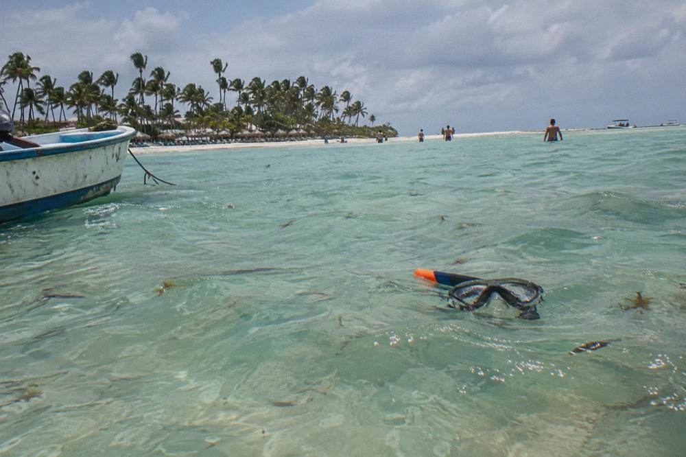 Shallow turquoise water over a sandy bottom with a sandbar in the distance