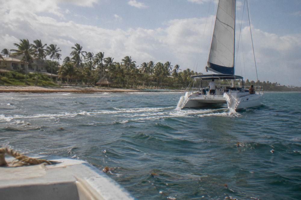 Small private catamaran cruising along the Bavaro coastline in late afternoon light