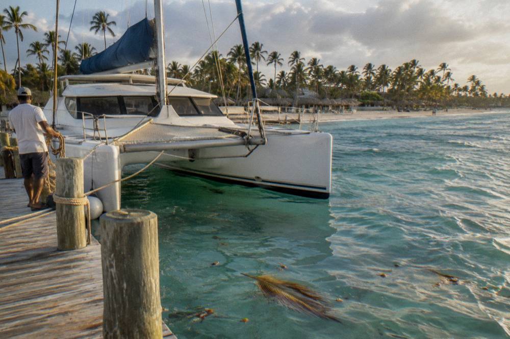 Private catamaran moored at a beach club dock at golden hour