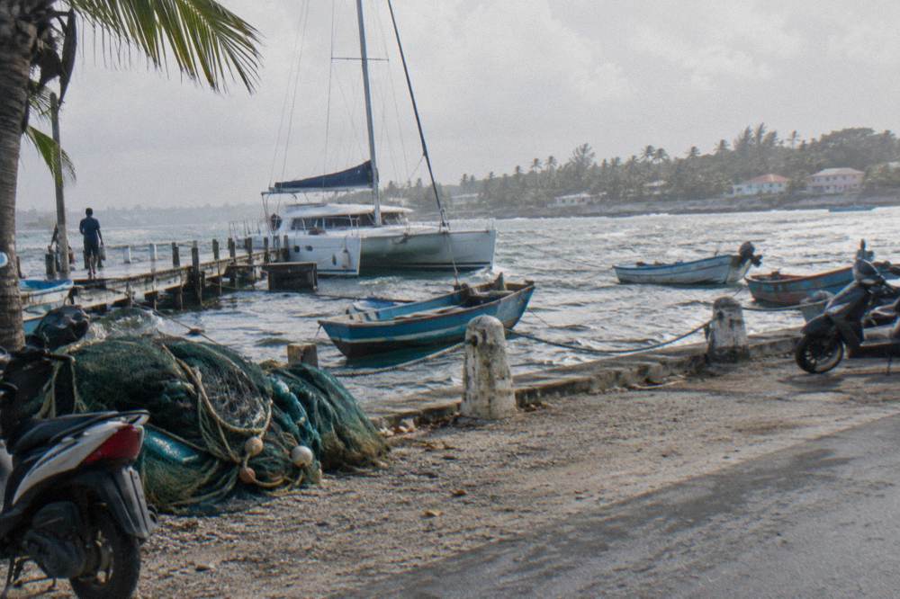 A catamaran moored at a wooden dock at Bayahibe with small fishing boats nearby