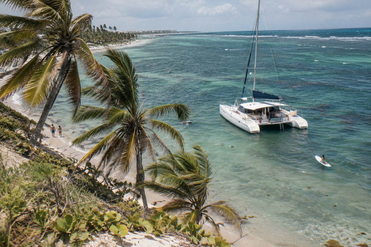 A large catamaran anchored in shallow turquoise water near a natural pool sandbar off the Bavaro coast
