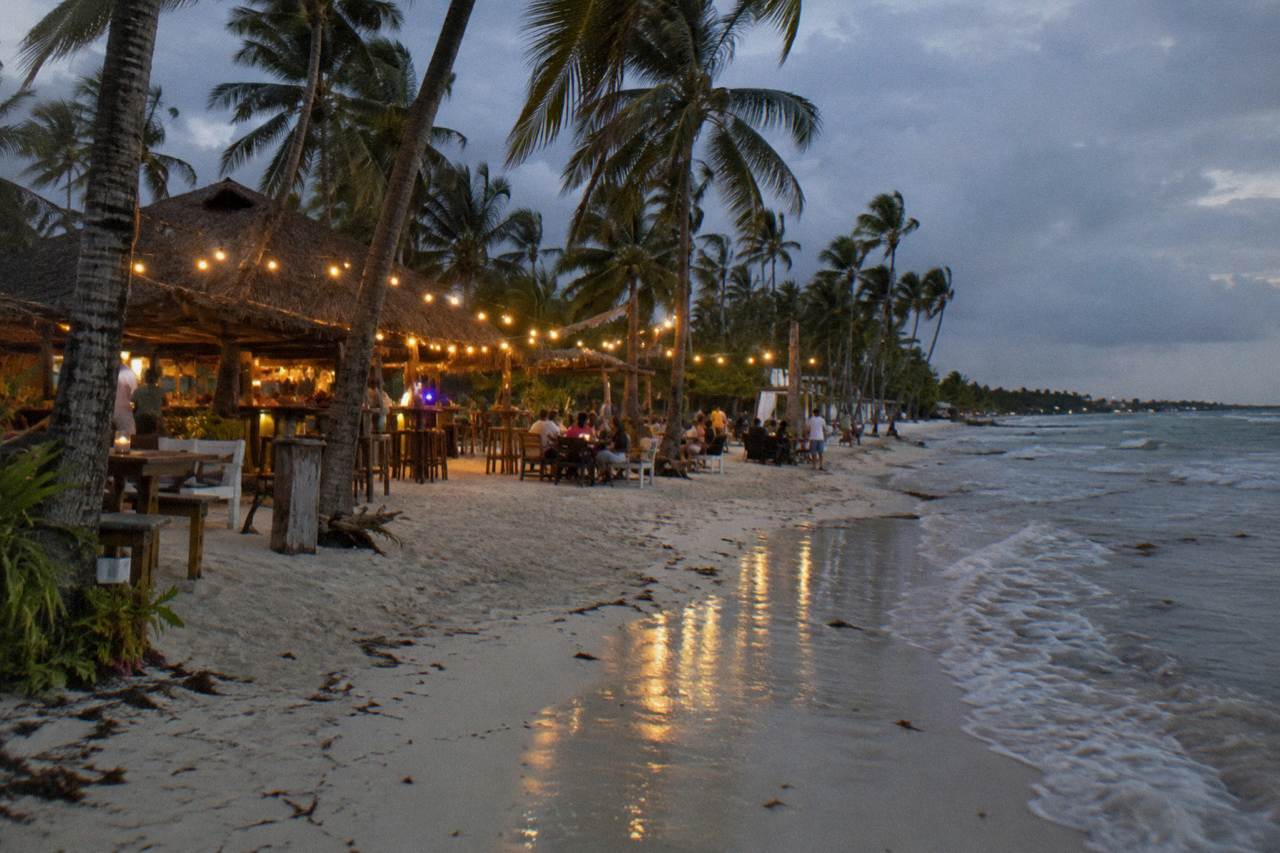 Open-air beach bar with string lights glowing above palm trees after dark along the Bavaro coastline