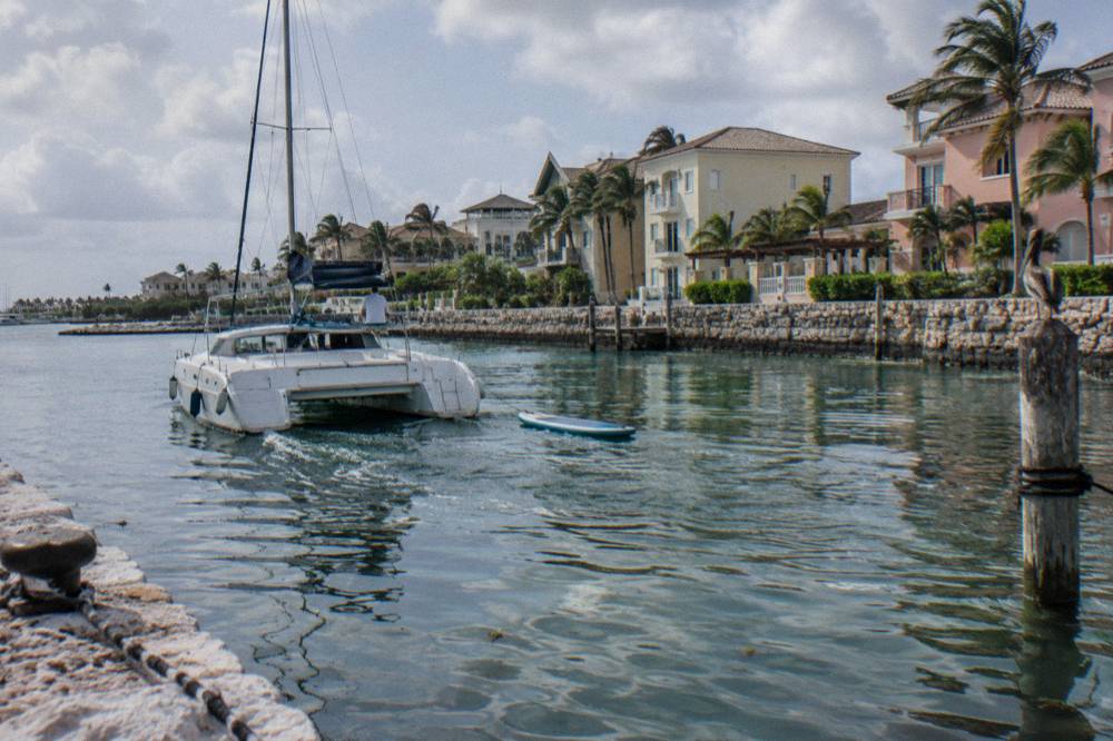 A small catamaran with a paddleboard floating beside it in calm turquoise water