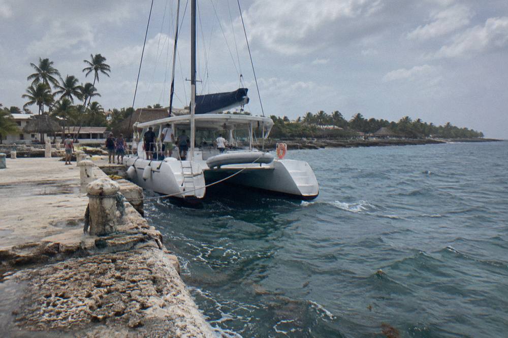 A moored catamaran with passengers boarding at a small port in the morning