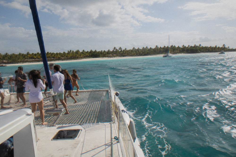 Guests dancing on the deck of a catamaran with music playing under an open sky