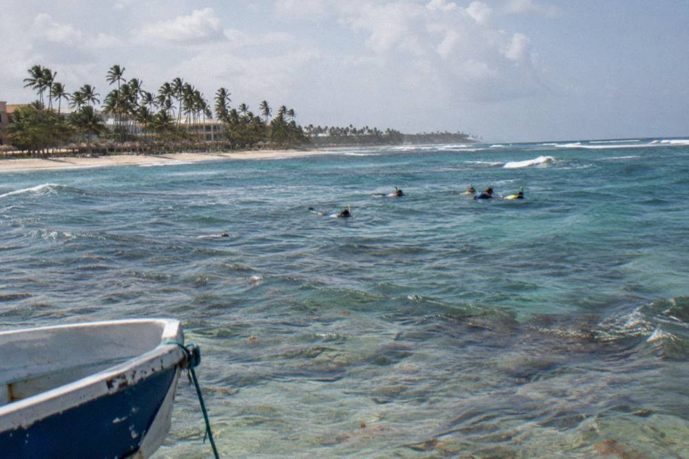 Snorkelers floating above a shallow coral reef in clear blue water