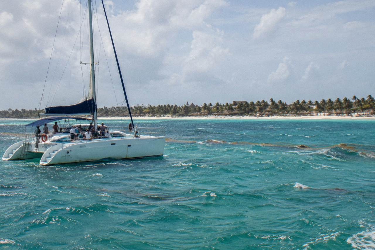 Open catamaran on calm turquoise water off the Punta Cana coast with distant white sandbar