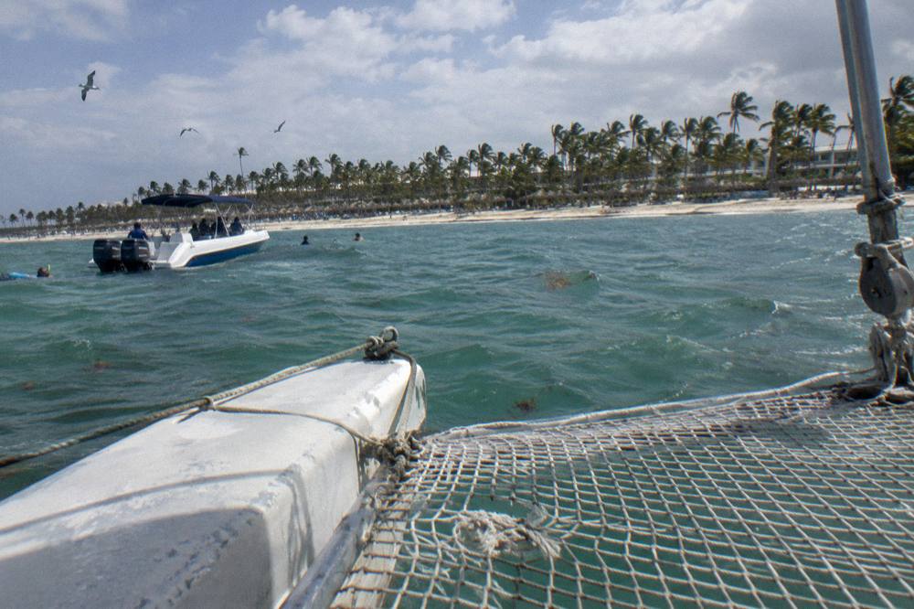 Catamaran netting over shallow clear water with snorkel boat nearby