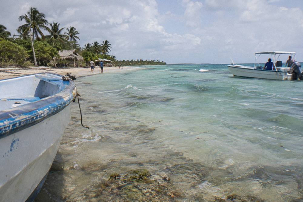 A private catamaran moored at a shallow sandbar with calm water and clear sky