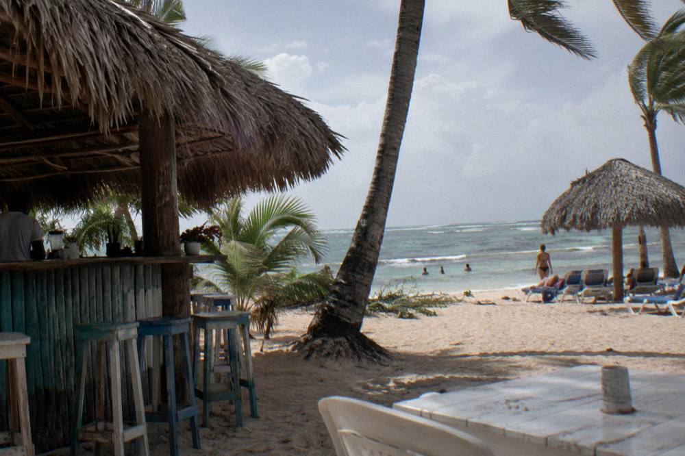 Beach bar and thatched umbrellas on white sand under an afternoon sky